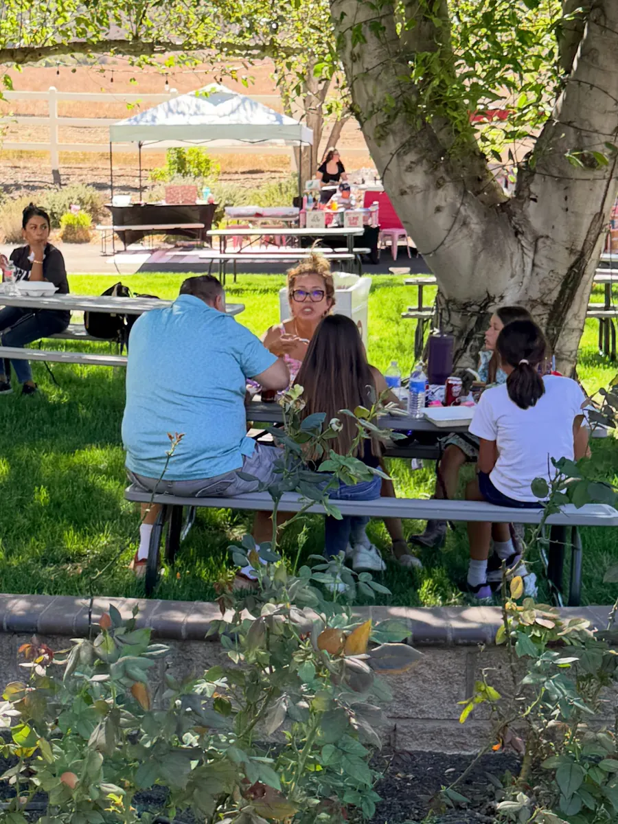 Guests at the picnic tables under the trees during the Grand Opening